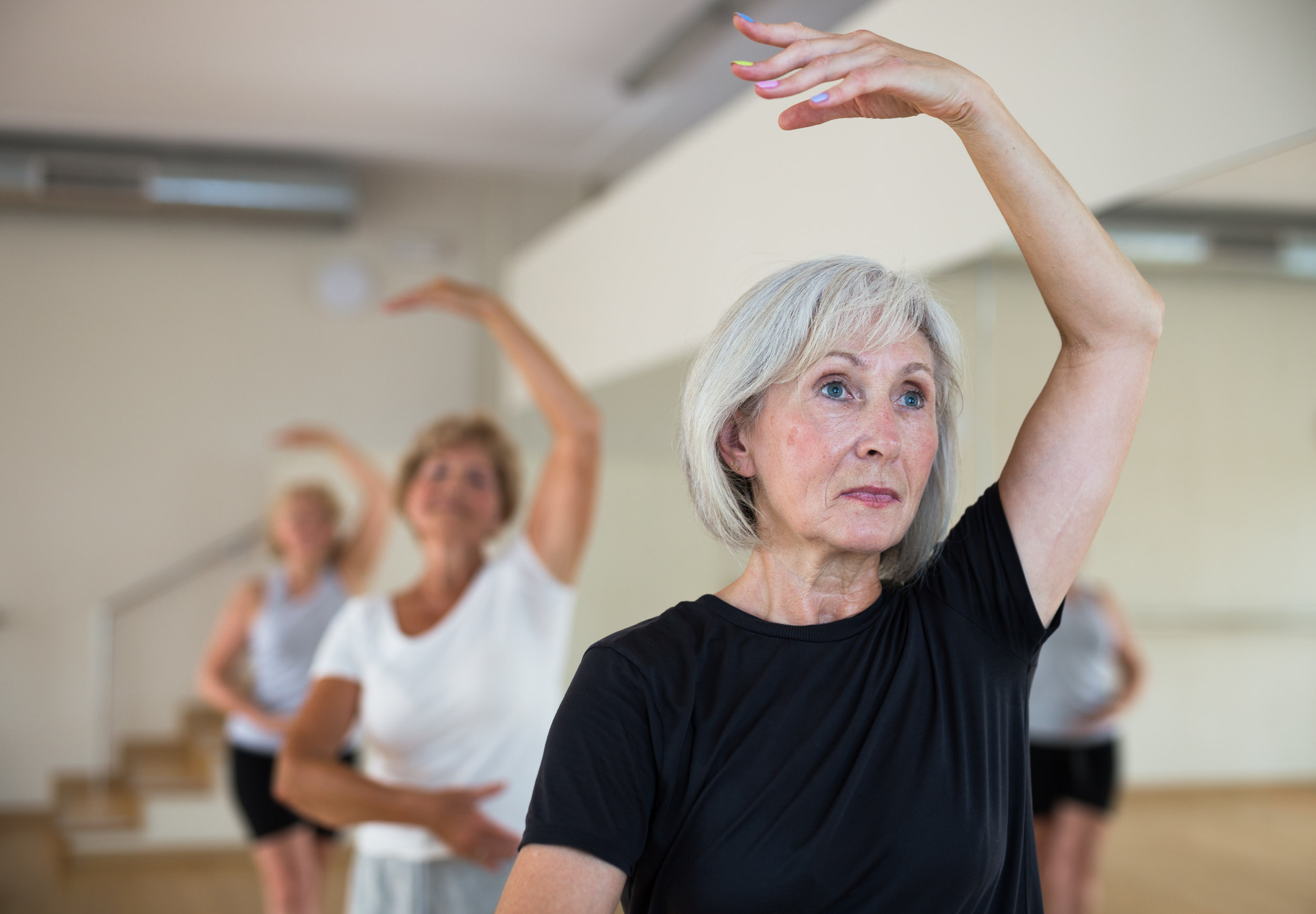 Aged women performing ballet dance in fitness room